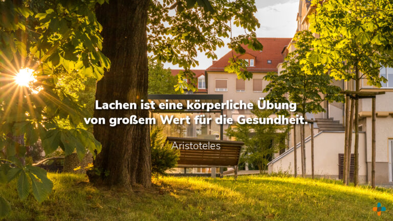 Bank in der Wiese vor Klinikum mit warmer Sonne