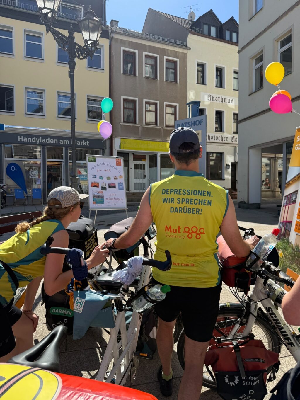 Zwei Personen der Mut-Tour auf Fahrrädern mit Trikots mit der Aufschrift „Depressionen. Wir sprechen darüber!“