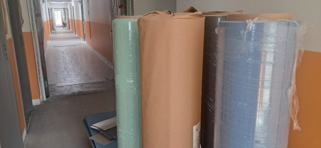 Aufgewickelte Bodenbeläge und Linoleumrollen für die Verlegung im Flur einer Baustelle.